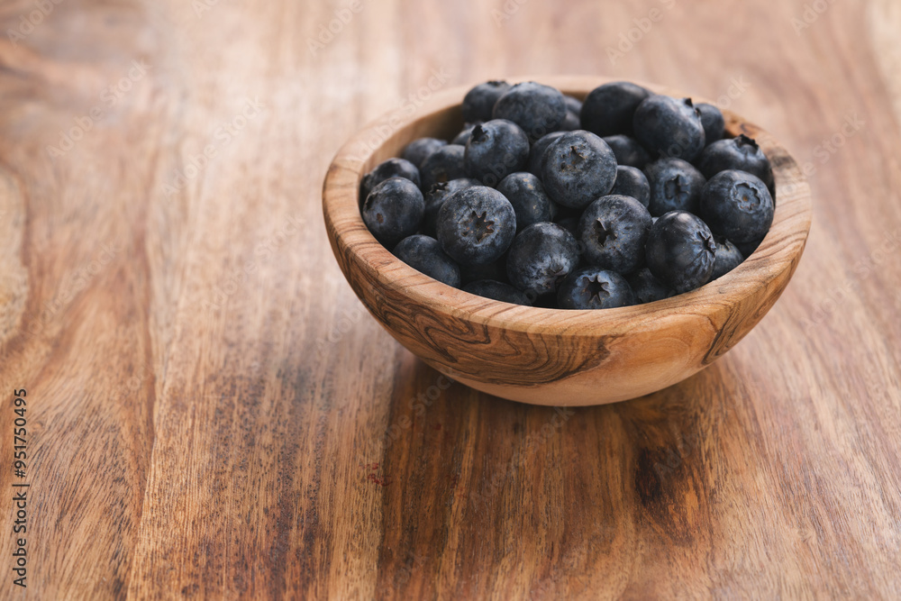 Fresh blueberries in wood bowl on table slightly toned Fresh blueberries in wood bowl on table slightly toned