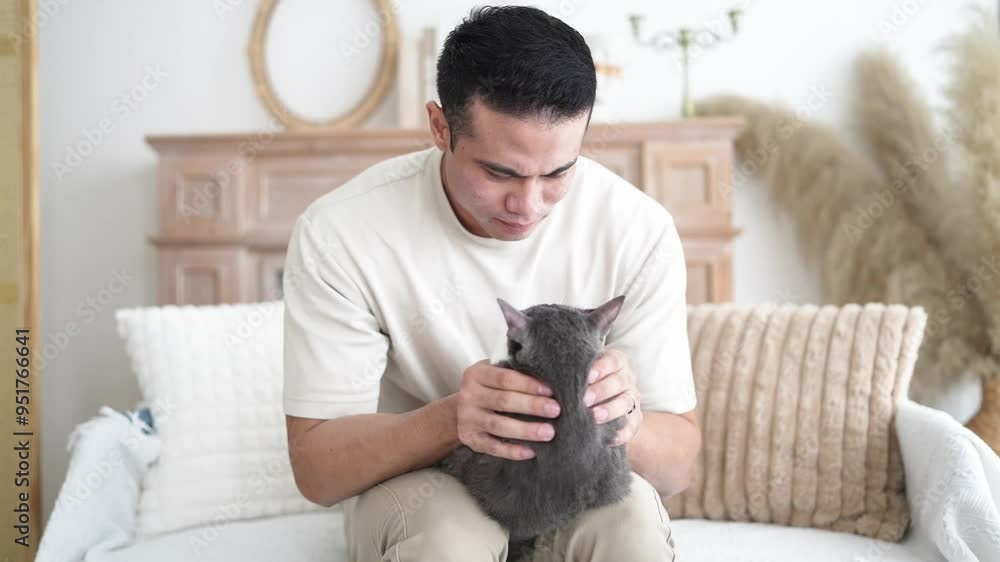 Chinese and Indian Malaysian couple in their 20s and 30s playing with a cat in a room with Western-style furniture in a house in Selangor, Malaysia. Chinese and Indian Malaysian couple in their 20s and 30s playing with a cat in a room with Western-style furniture in a house in Selangor, Malaysia.