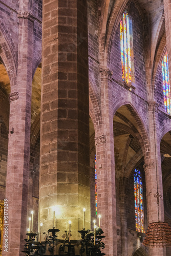 Impressive gothic style architecture inside main and side naves of Cathedral with columns, ceiling and altar, glass mural windows and daylight with religious elements and decoration photo