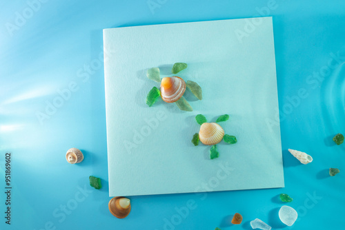 Photography Artistic arrangement of seashell and sea glass pieces on blue background, forming a turtle shape