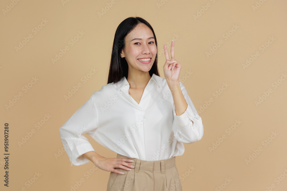 Smiling Woman Showing Peace Sign, Beige Background Smiling Woman Showing Peace Sign, Beige Background