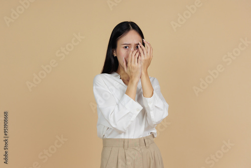 Fearful Woman Covering Face with Hands, Beige Background