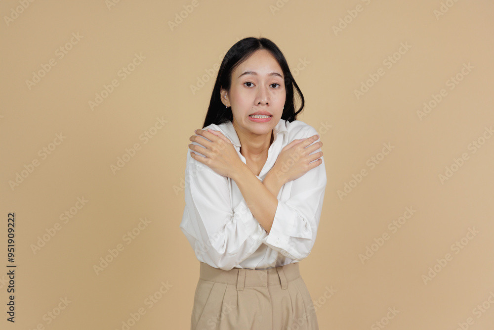 Cold Woman Hugging Herself, Shivering with Chilly Expression, Beige Background Cold Woman Hugging Herself, Shivering with Chilly Expression, Beige Background
