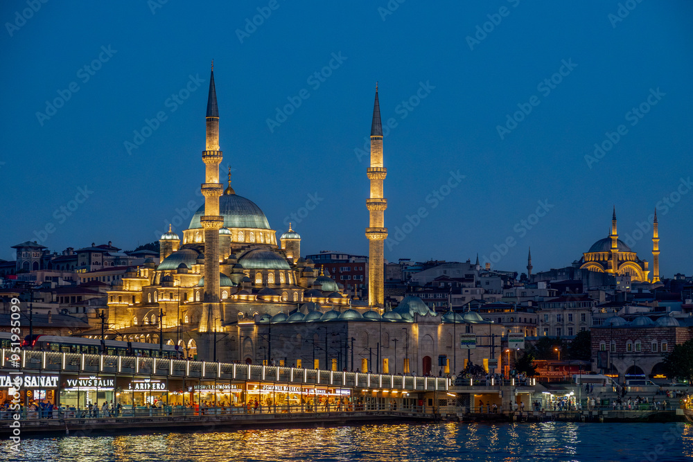 Naklejka premium Türkiye. Istanbul. The new mosque or Valide Sultan Camii with the Galata bridge and ın the background the suleymaniye mosque at dusk