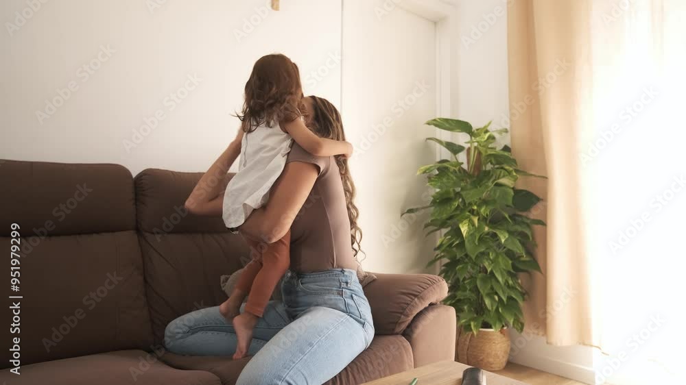 Loving mother embracing adorable girl on sofa at home Loving mother embracing adorable girl on sofa at home