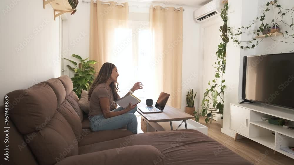 Happy woman writing in diary while working on laptop at home Happy woman writing in diary while working on laptop at home