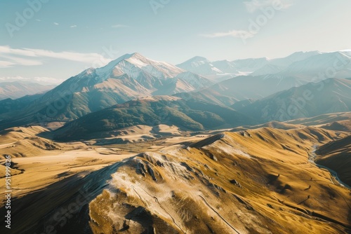 Wallpaper Mural An expansive view of golden valleys and mountain peaks lightly dusted with snow during sunrise, capturing the beauty and tranquility of a pristine landscape. Torontodigital.ca