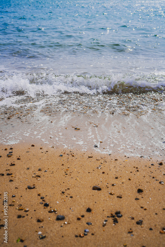 Sea Waves Crashing on Beach Sand with Stones and shells on the shore