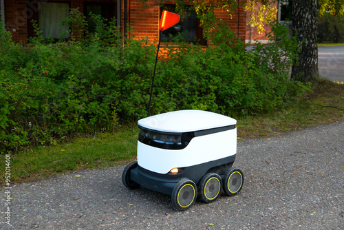 A delivery robot on wheels completes a home delivery from the grocery store. The self-driving courier navigates traffic on the road. Efficient shipping ensures quick takeaway service.