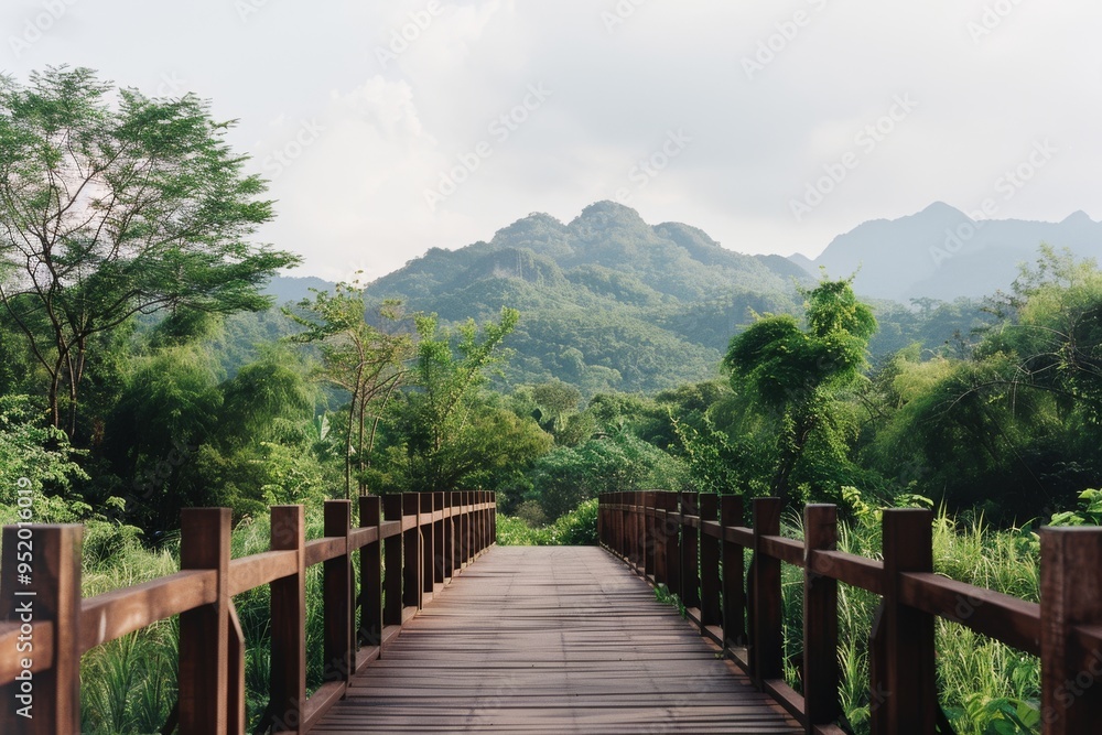 A picturesque wooden bridge leads towards lush, green mountains, inviting a peaceful stroll in nature's tranquility. A picturesque wooden bridge leads towards lush, green mountains, inviting a peaceful stroll in nature's tranquility.
