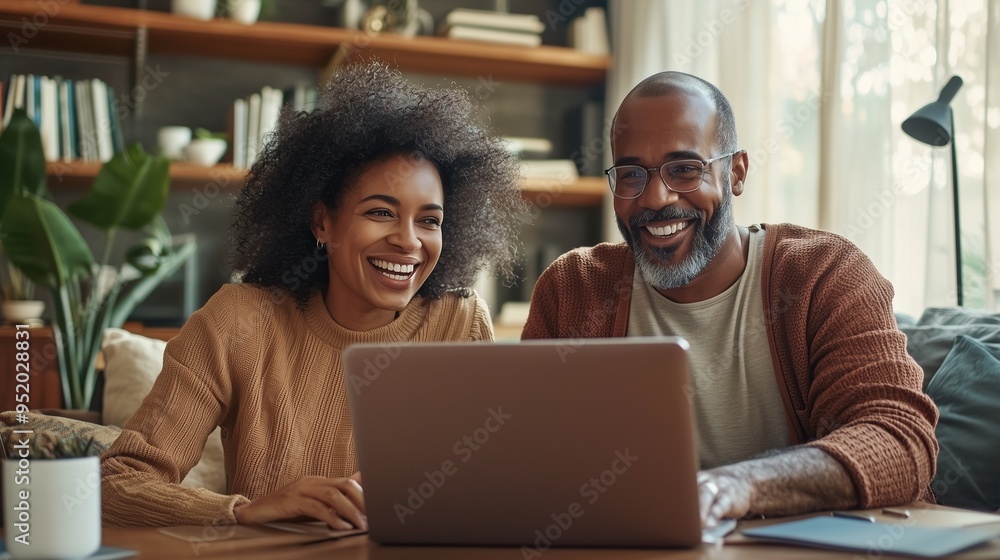 Young couple smiling while discussing finances with their advisor via video call, laptop and home office setting visible. Young couple smiling while discussing finances with their advisor via video call, laptop and home office setting visible.