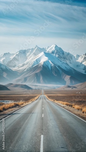 A straight road stretches into the distance, leading towards a range of snow-capped mountains.