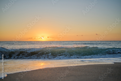 Waves crashing into beach at sunrise or sunset