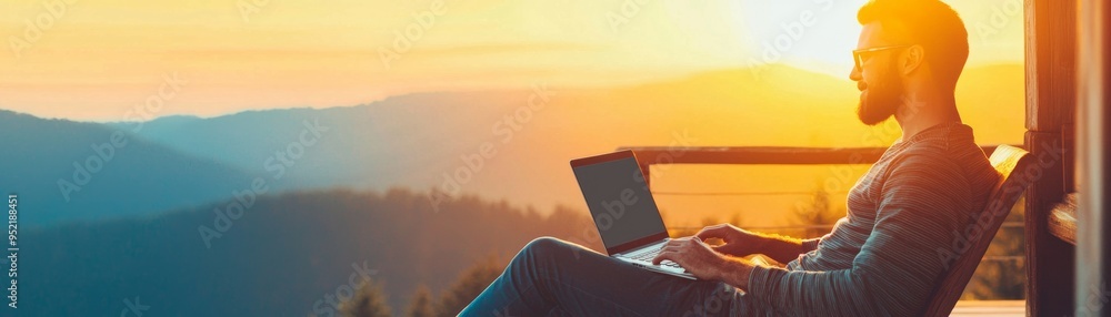 A man enjoys a serene evening working on his laptop while watching the sunset over the mountains. A man enjoys a serene evening working on his laptop while watching the sunset over the mountains.