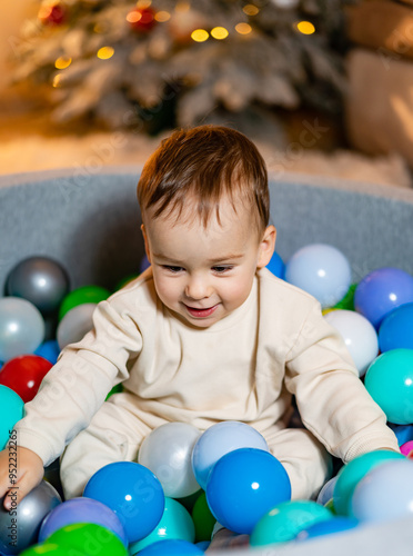Toddler playing joyfully in a colorful ball pit during winter season. A happy toddler is enjoying playtime in a vibrant ball pit surrounded by colorful plastic balls