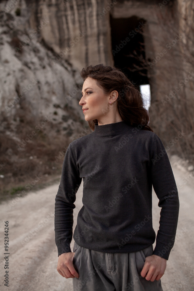 A beautiful woman dressed in gray pants and a sweater walks against the background of a career in stylish clothes A beautiful woman dressed in gray pants and a sweater walks against the background of a career in stylish clothes