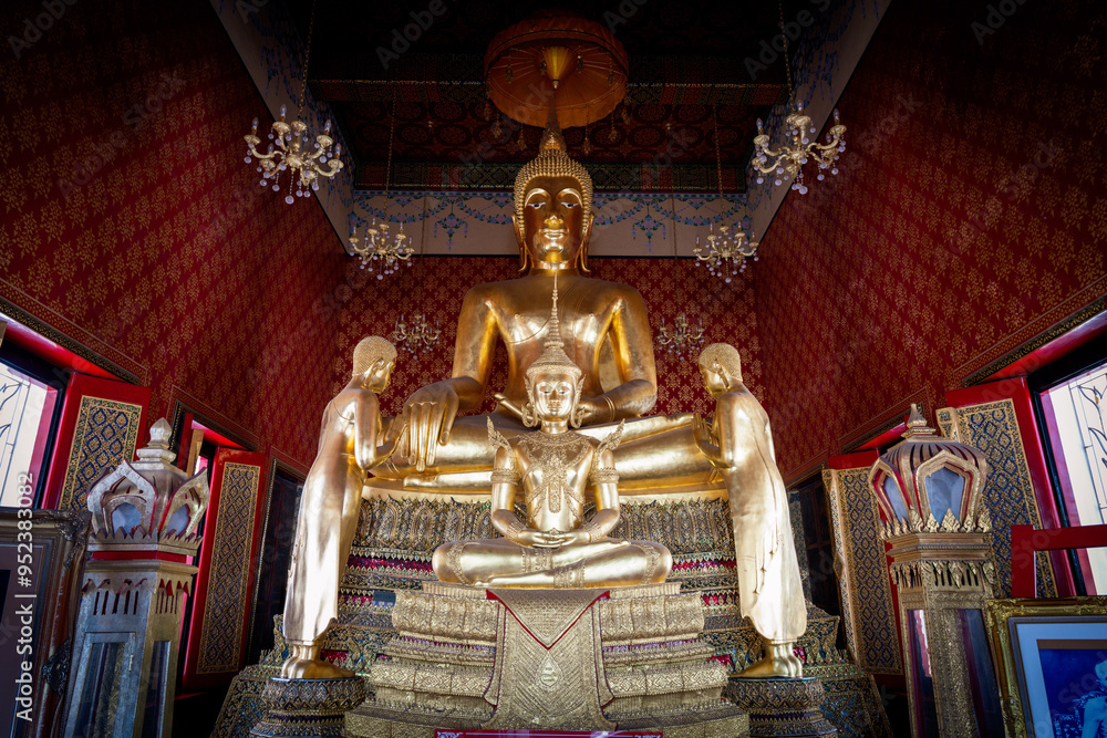 Obraz premium Thailand, August 11, 2024, Wat Phitchaya Yatikaram Worawihan, Golden Buddha statue in ornate temple surrounded by intricate decor and figures during daylight in Thailand