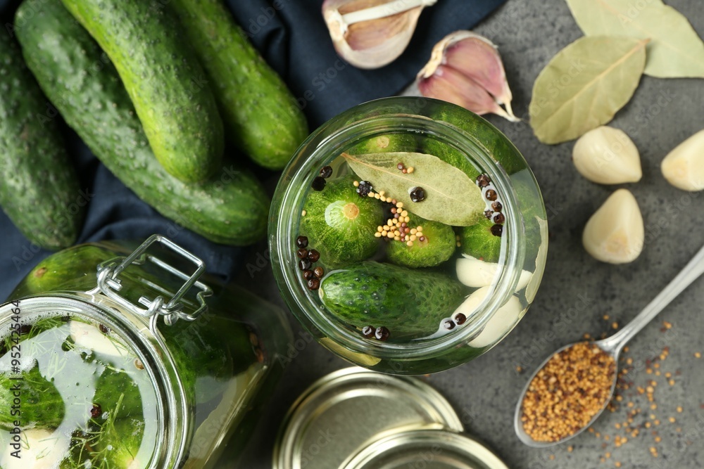 Making pickles. Fresh cucumbers and spices in jars on grey table, flat lay Making pickles. Fresh cucumbers and spices in jars on grey table, flat lay