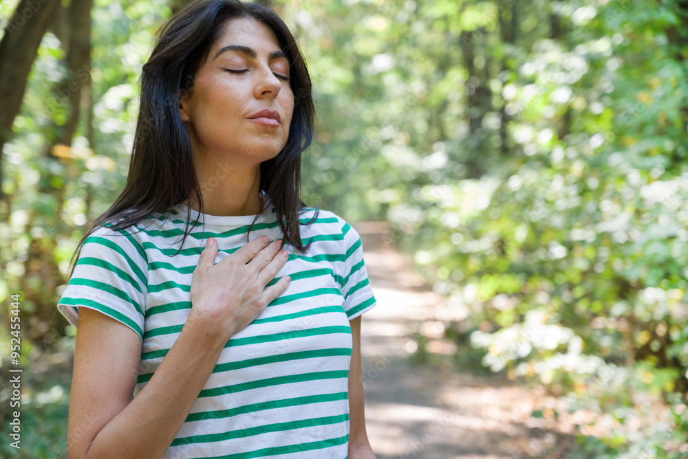 Relaxed woman breathing fresh air in a green summer forest and making breathing exercises Relaxed woman breathing fresh air in a green summer forest and making breathing exercises