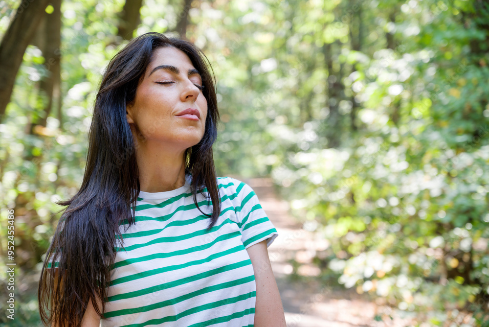Relaxed woman breathing fresh air in a green summer forest and making breathing exercises Relaxed woman breathing fresh air in a green summer forest and making breathing exercises