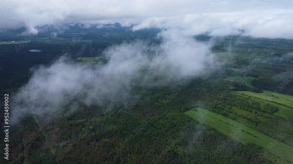 Vol de drone a haute altitude au travers un ciel nuageux laissant percevoir une forêt verdoyante et quelques champs cultivés. Vol de drone a haute altitude au travers un ciel nuageux laissant percevoir une forêt verdoyante et quelques champs cultivés.