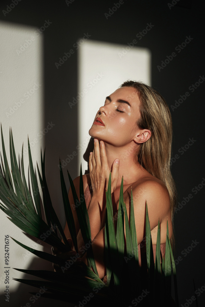 © blackday - Young woman with blonde hair is holding a palm leaf in sunlight © blackday - Young woman with blonde hair is holding a palm leaf in sunlight
