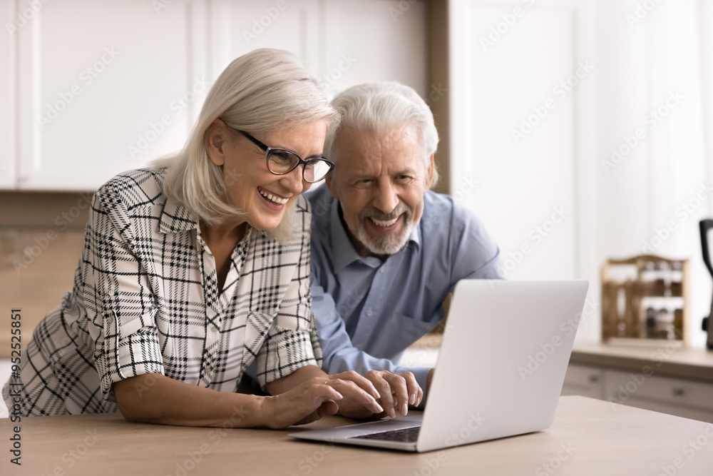 Smiling aged wife and husband websurfing information on internet spend free time online, chatting, searching, browsing enjoy remote purchases using laptop and marketplace website. Pastime, modern tech Smiling aged wife and husband websurfing information on internet spend free time online, chatting, searching, browsing enjoy remote purchases using laptop and marketplace website. Pastime, modern tech