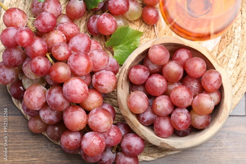 Fresh ripe grapes and glass of wine on wooden table, flat lay