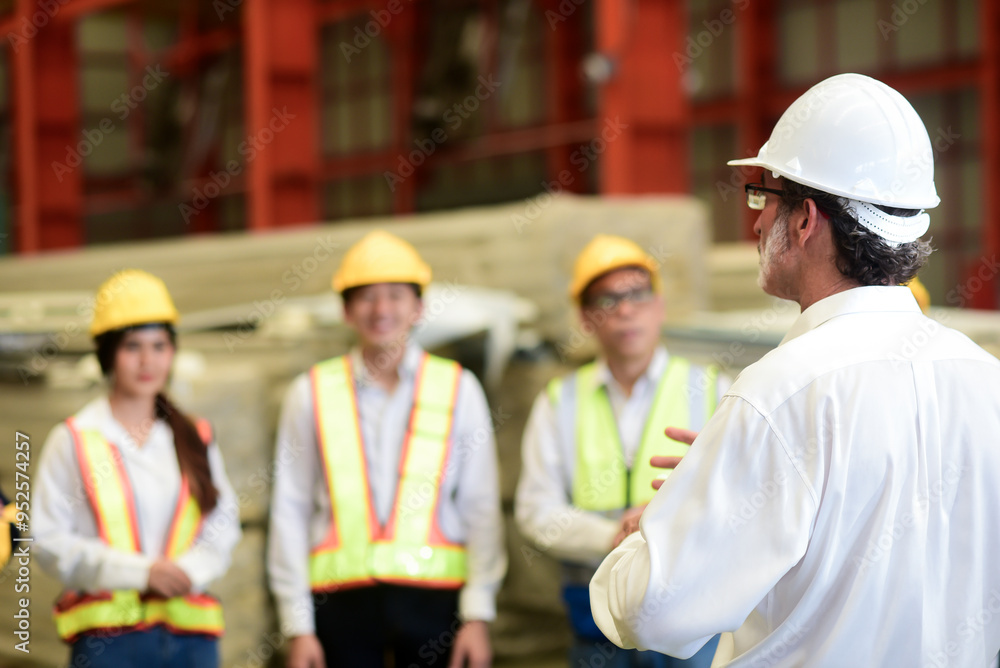 Professional Caucasian manager engineer wearing safety hardhat is training industry worker, workshop factory operator, mechanical engineering team production in heavy industrial manufacture factory. Professional Caucasian manager engineer wearing safety hardhat is training industry worker, workshop factory operator, mechanical engineering team production in heavy industrial manufacture factory.