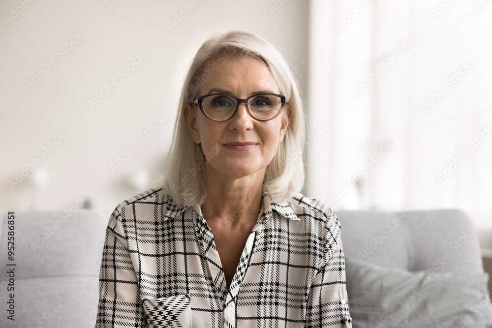 Head shot portrait attractive mature woman in glasses sit on sofa looking at camera, take part in telemedicine appointment with doctor, get consultation, engaged in communication with family, webcam Head shot portrait attractive mature woman in glasses sit on sofa looking at camera, take part in telemedicine appointment with doctor, get consultation, engaged in communication with family, webcam