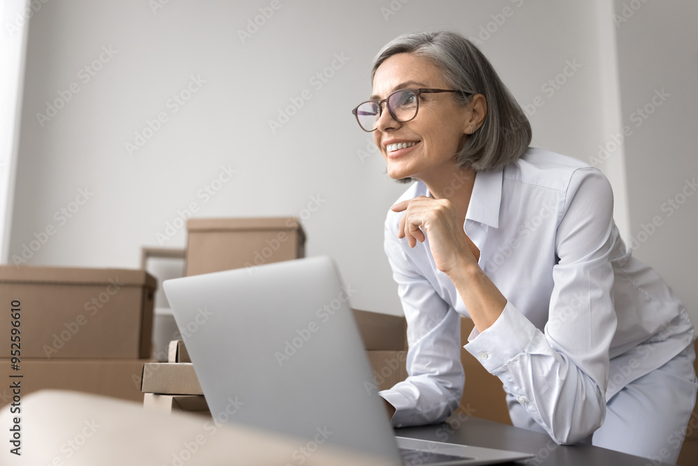 Small business owner leaned at desk with laptop working from stockroom, stacked sealed boxes in background. Respond on clients enquiries, review positive feedbacks, managing orders, enjoy sales growth Small business owner leaned at desk with laptop working from stockroom, stacked sealed boxes in background. Respond on clients enquiries, review positive feedbacks, managing orders, enjoy sales growth