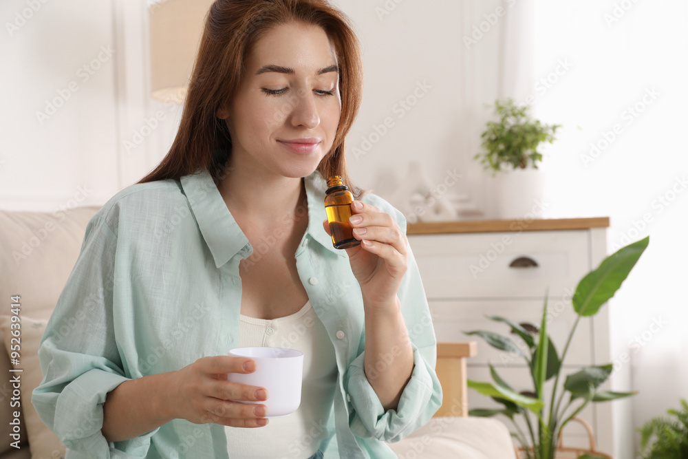 Woman with bottle of essential oil and aroma diffuser at home Woman with bottle of essential oil and aroma diffuser at home