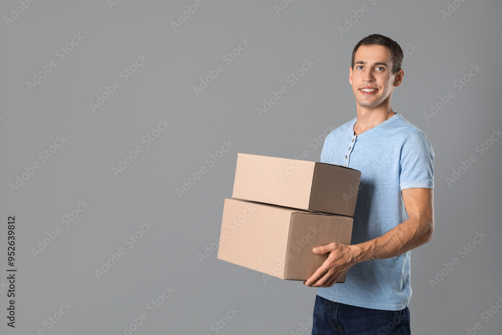 Moving into new house. Man with cardboard boxes on grey background, space for text Moving into new house. Man with cardboard boxes on grey background, space for text