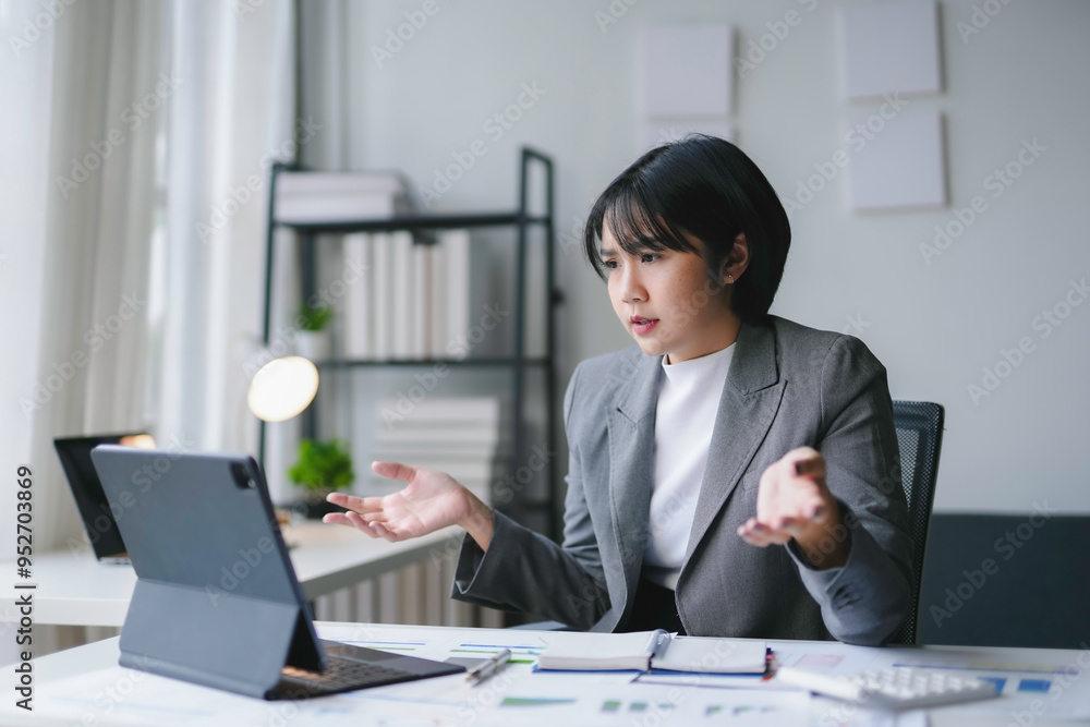 Businesswoman is gesturing with frustration while looking at a tablet and working in her office Businesswoman is gesturing with frustration while looking at a tablet and working in her office