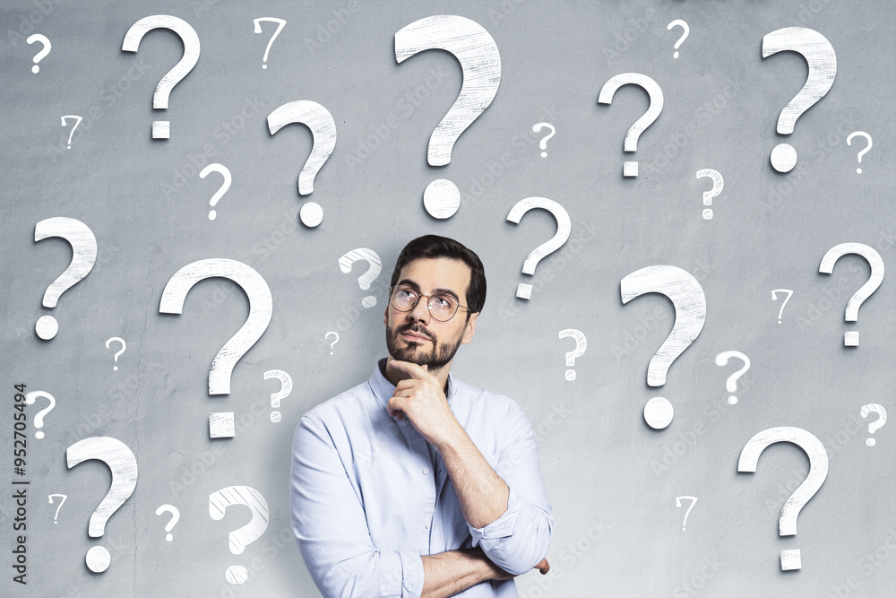 Thoughtful man surrounded by question marks on a gray background, symbolizing uncertainty and seeking answers. Thoughtful man surrounded by question marks on a gray background, symbolizing uncertainty and seeking answers.