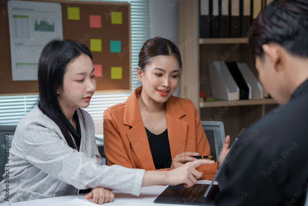 Two businesswomen and a businessman working together in the office, brainstorming and discussing a project Two businesswomen and a businessman working together in the office, brainstorming and discussing a project