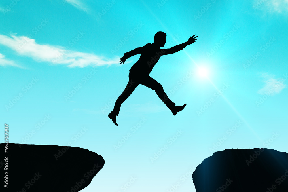 Silhouette of a man jumping between cliffs against a bright sky. Silhouette of a man jumping between cliffs against a bright sky.