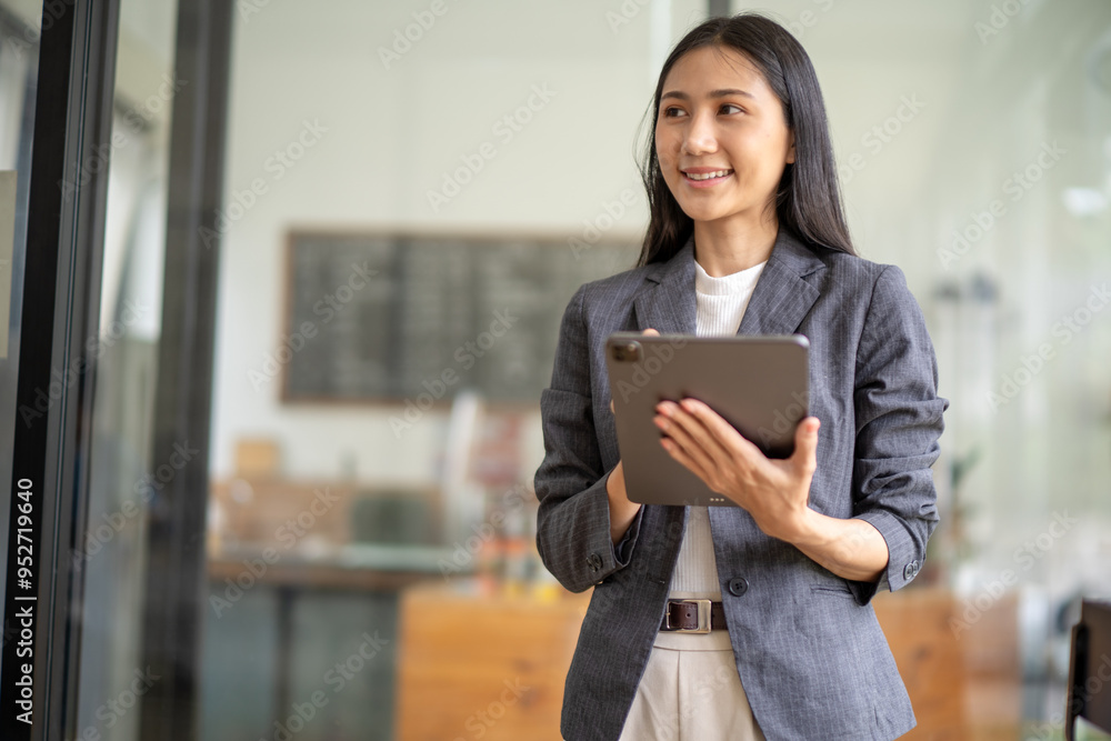 A woman wearing a gray jacket and holding a tablet A woman wearing a gray jacket and holding a tablet