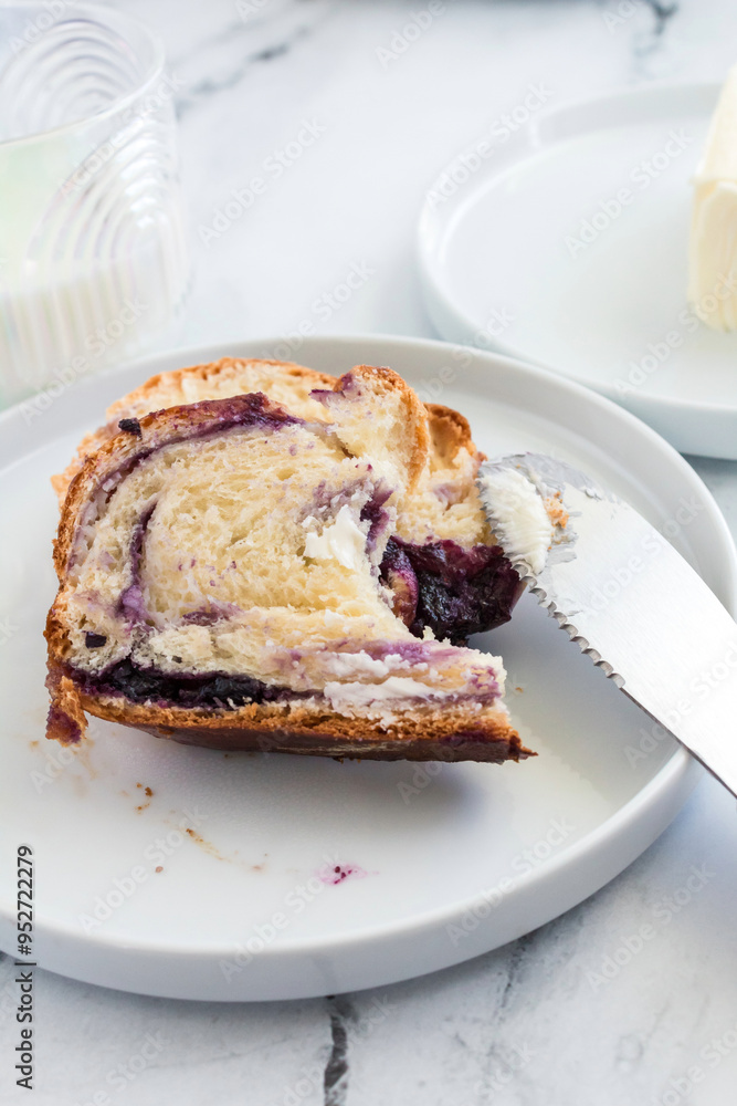 Slice of blueberry cream cheese babka on a white plate with a knife Slice of blueberry cream cheese babka on a white plate with a knife