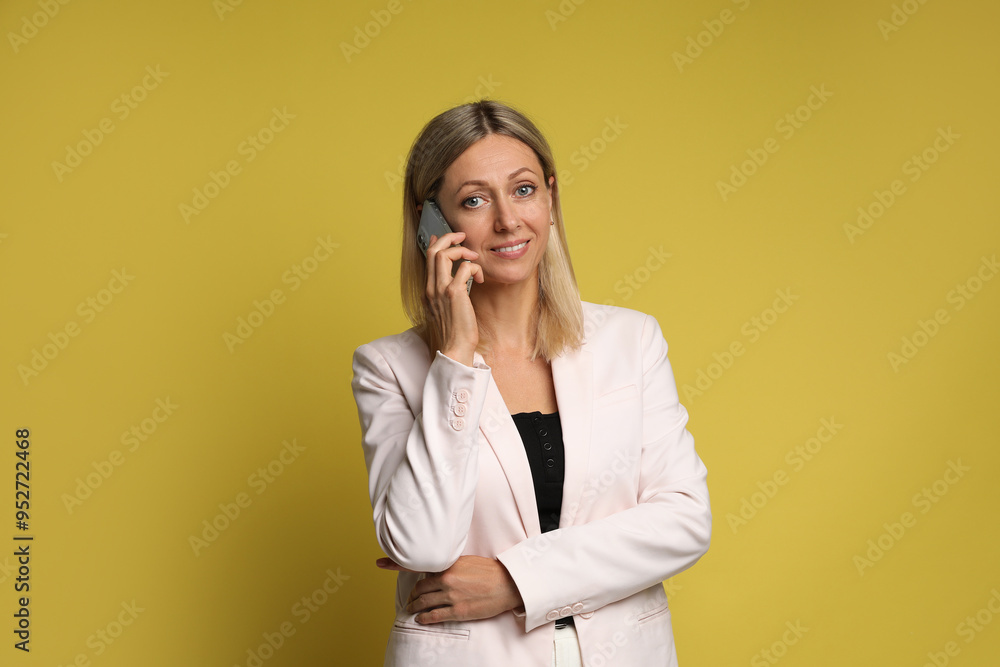 Beautiful smiling woman talking on smartphone against yellow background Beautiful smiling woman talking on smartphone against yellow background