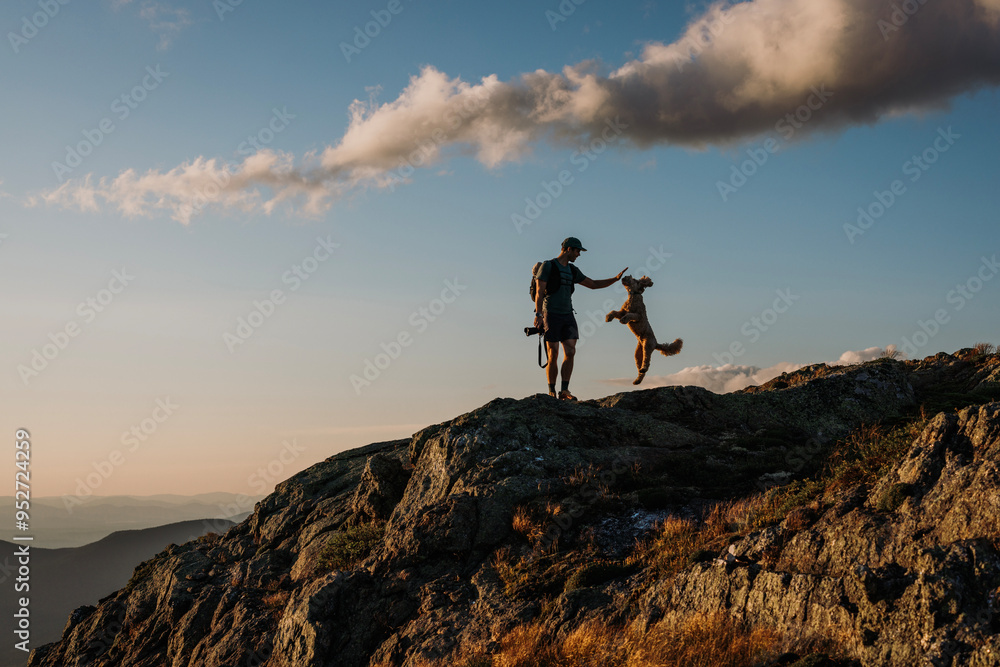 Hiker and his excited jumping dog at sunset in White Mountains, NH