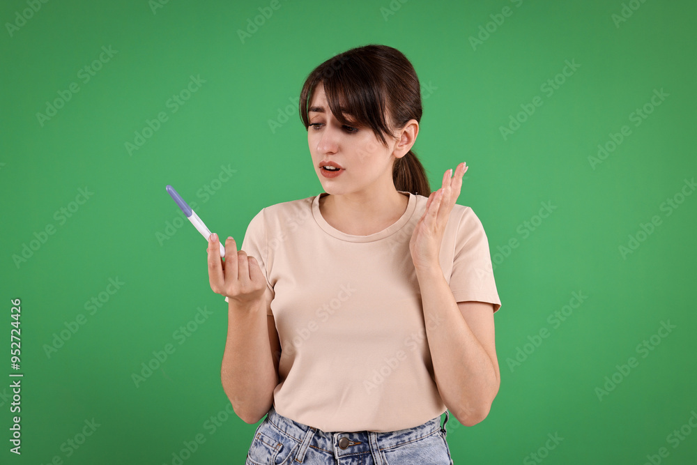 Worried young woman with pregnancy test on green background Worried young woman with pregnancy test on green background