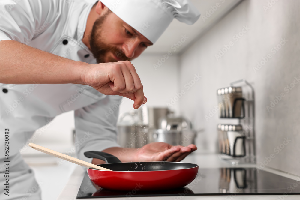 Professional chef adding salt into frying pan in kitchen Professional chef adding salt into frying pan in kitchen