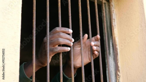 imprisonment symbol - hands of black man grab the bars of the window