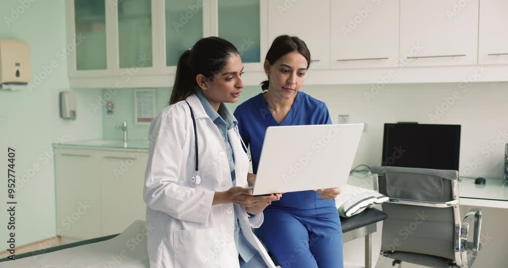Two female medical workers in uniform using laptop, collaborating, working together, sharing experiences and insights, solve treatment plan while review health test results, discuss upcoming operation Two female medical workers in uniform using laptop, collaborating, working together, sharing experiences and insights, solve treatment plan while review health test results, discuss upcoming operation