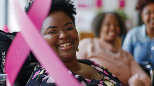 Young black Breast Cancer Survivor in a wheelchair smiling beaten cancer survive against odds. millenial 25 year old cancer supporter. Pink Ribbon Foundation. With family and friends. photo