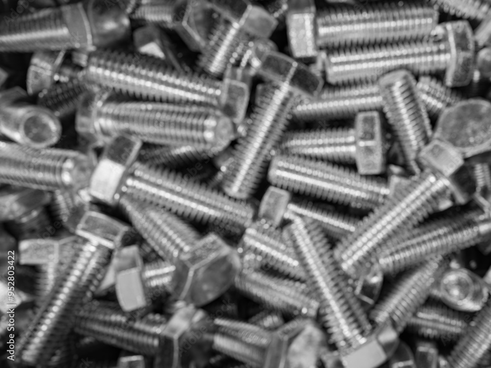 Metal bolts blurred industrial background. Group of shiny defocused threaded parts. Engineering or assembly concept texture Metal bolts blurred industrial background. Group of shiny defocused threaded parts. Engineering or assembly concept texture