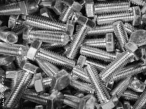 Metal bolts blurred industrial background. Group of shiny defocused threaded parts. Engineering or assembly concept texture photo