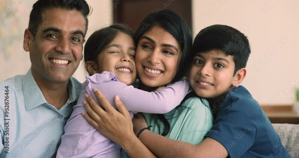 Happy young Indian parents cuddling little daughter and son with love, tenderness, affection, care, hugging sibling kids, looking at camera for portrait, smiling, laughing, enjoying family leisure Happy young Indian parents cuddling little daughter and son with love, tenderness, affection, care, hugging sibling kids, looking at camera for portrait, smiling, laughing, enjoying family leisure