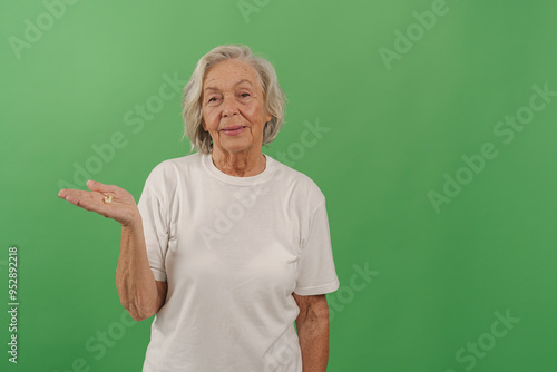 A cheerful elderly woman with gray hair happily gestures invitingly, radiating warmth against a lush green background